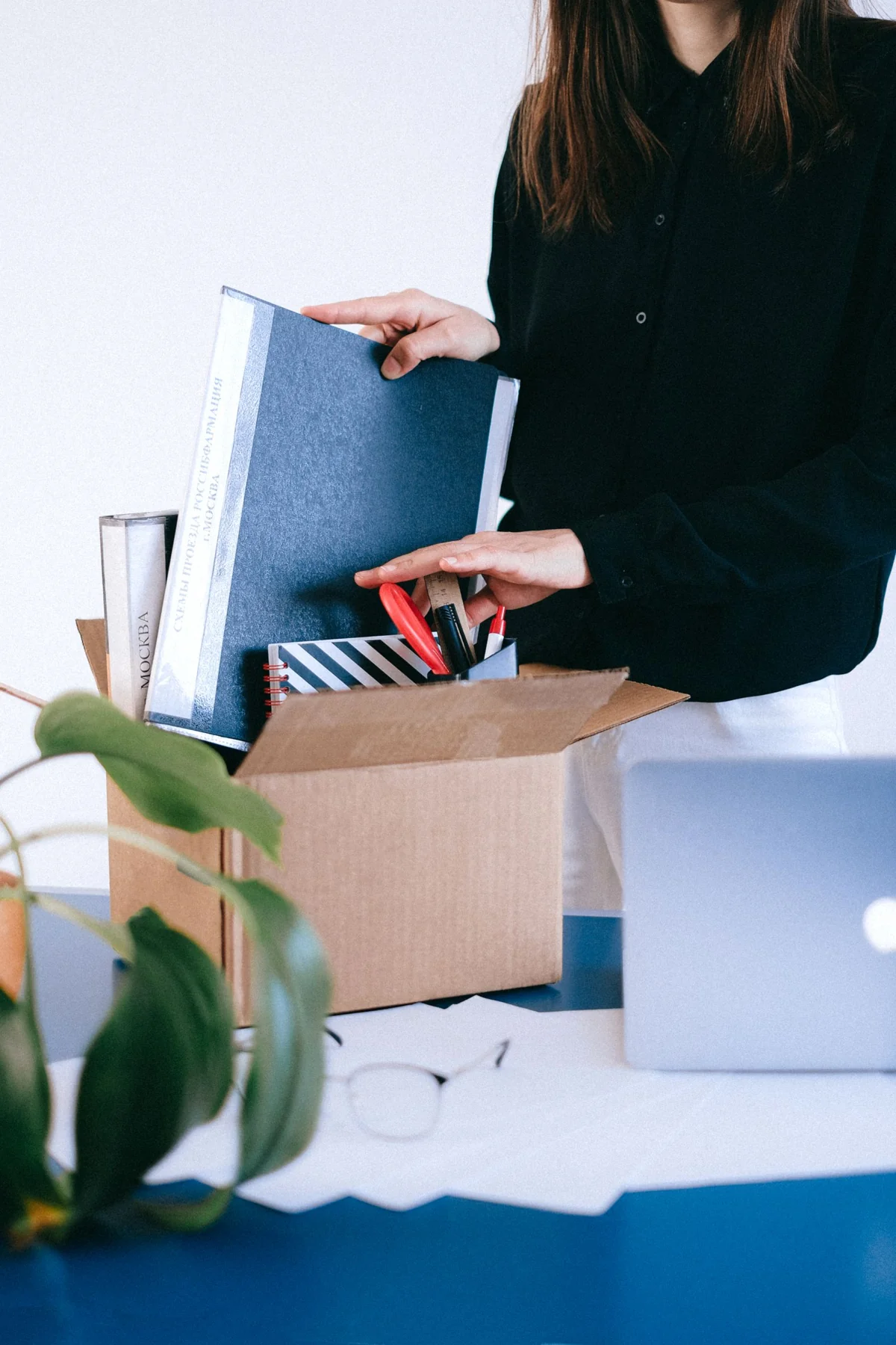 Büromaterial und Unterlagen werden am Schreibtisch in einen Karton gepackt.