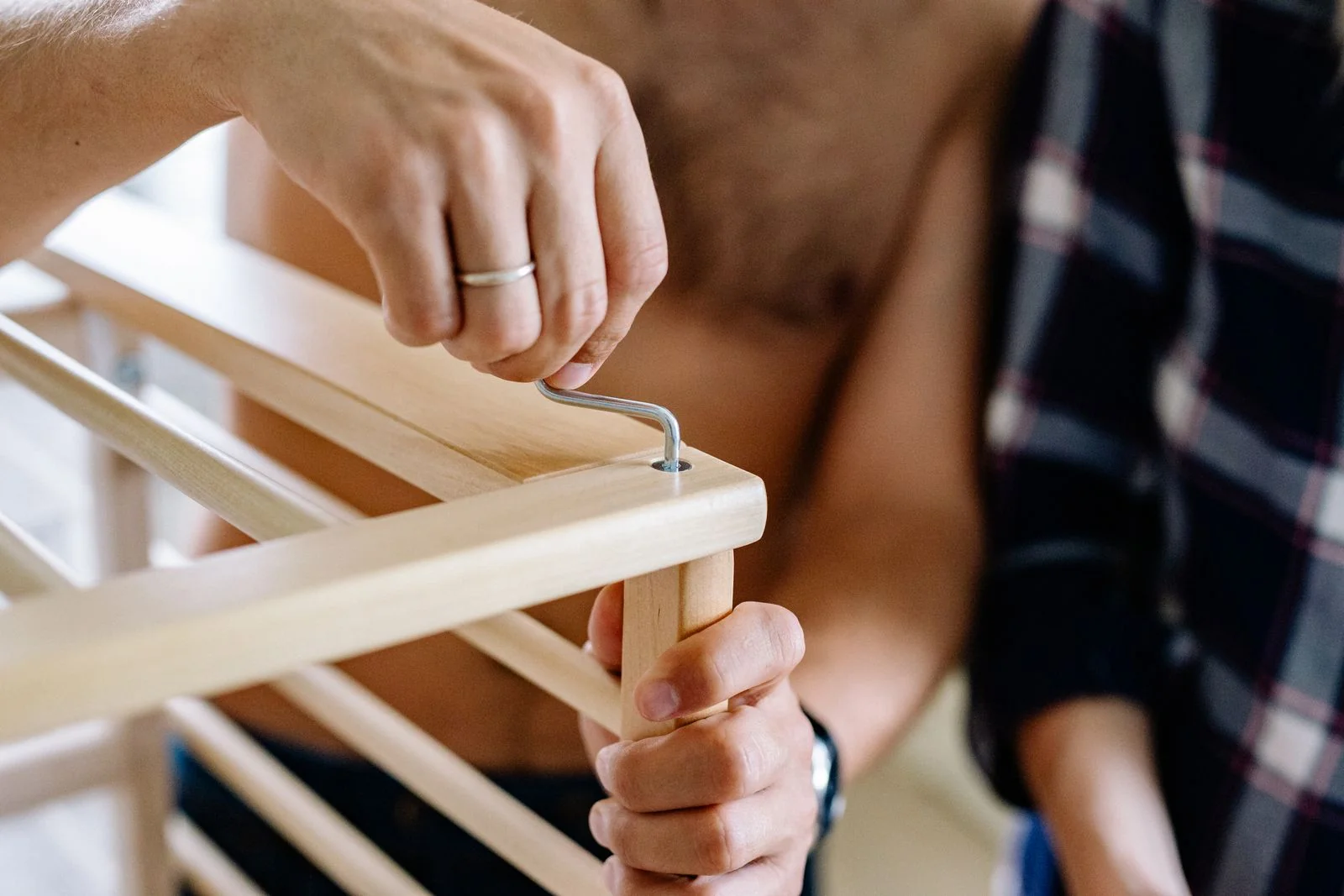 Hände verschrauben ein Holzmöbel mit einem Innensechskantschlüssel